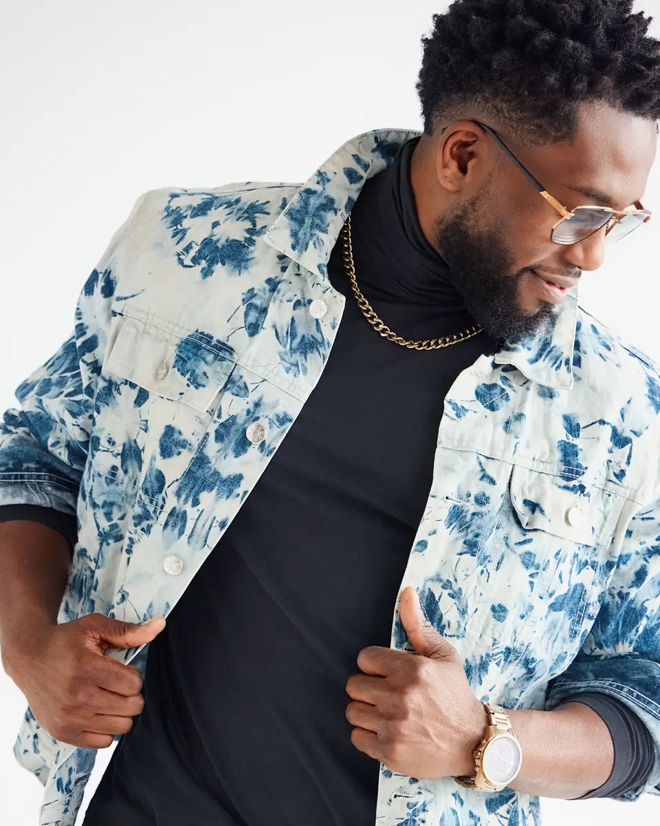 Chamalo in a printed denim jacket, looking down, in the studio